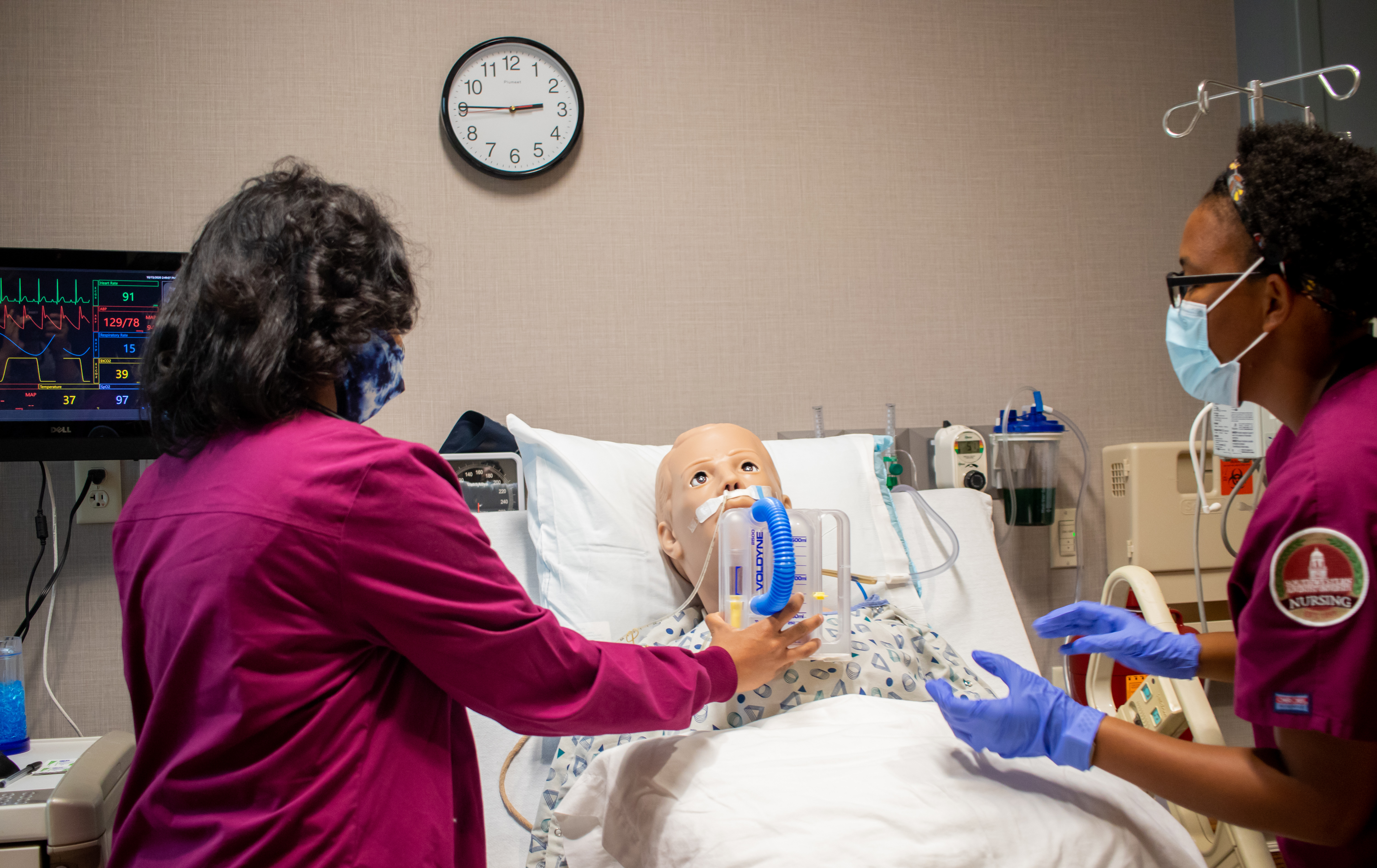 Two nurses caring for a medical simulation manikin