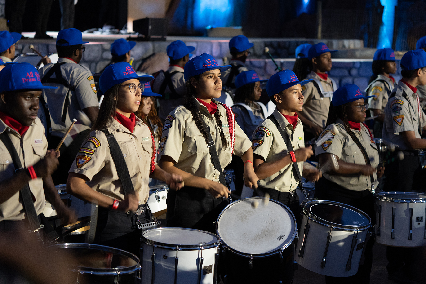 a multicultural group of young people drumming together in uniform.