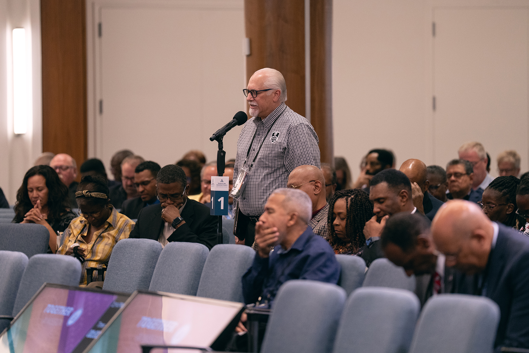 A white man standing in a crowd and praying.