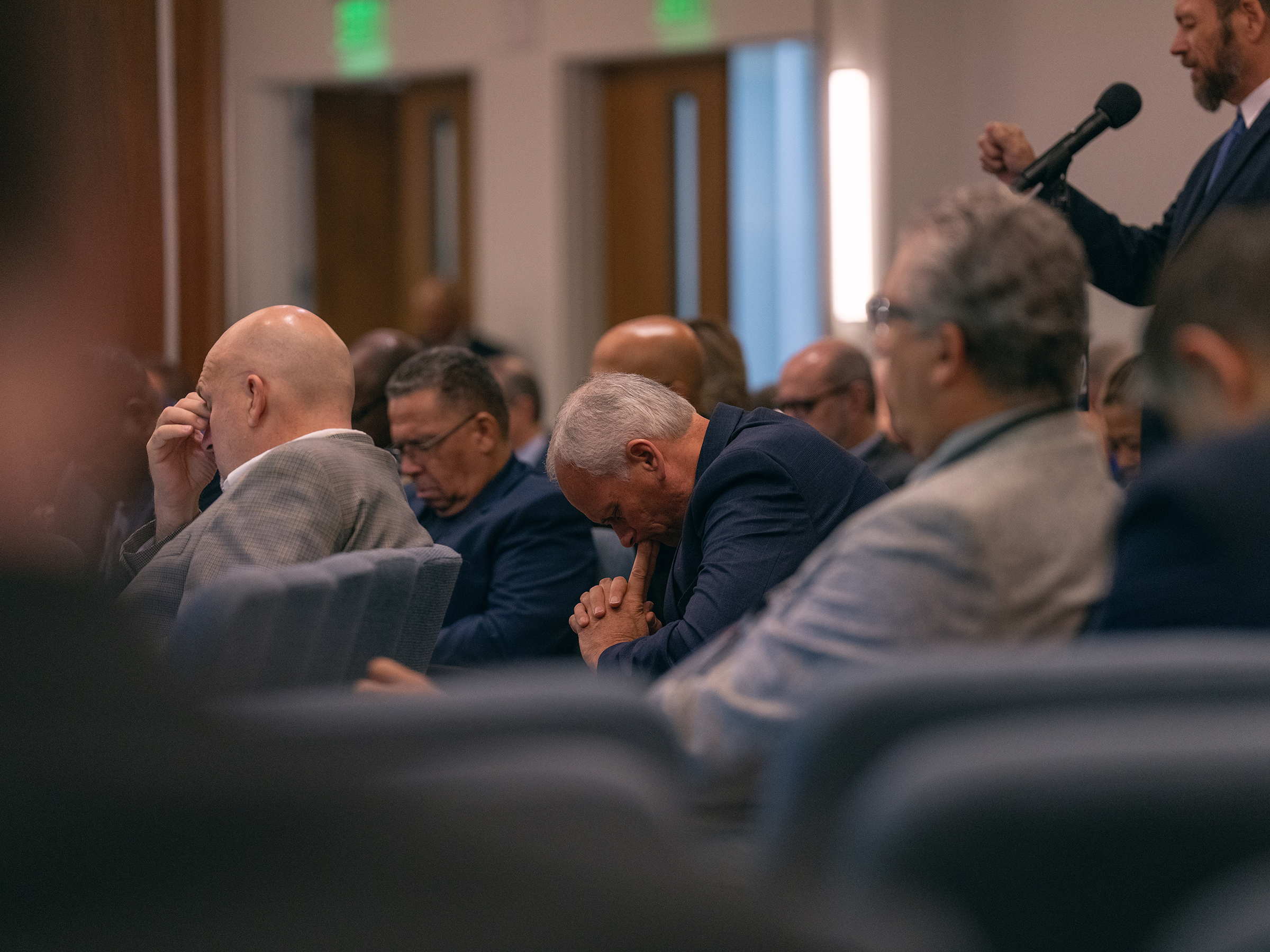 A group of people wearing business suits praying together. 