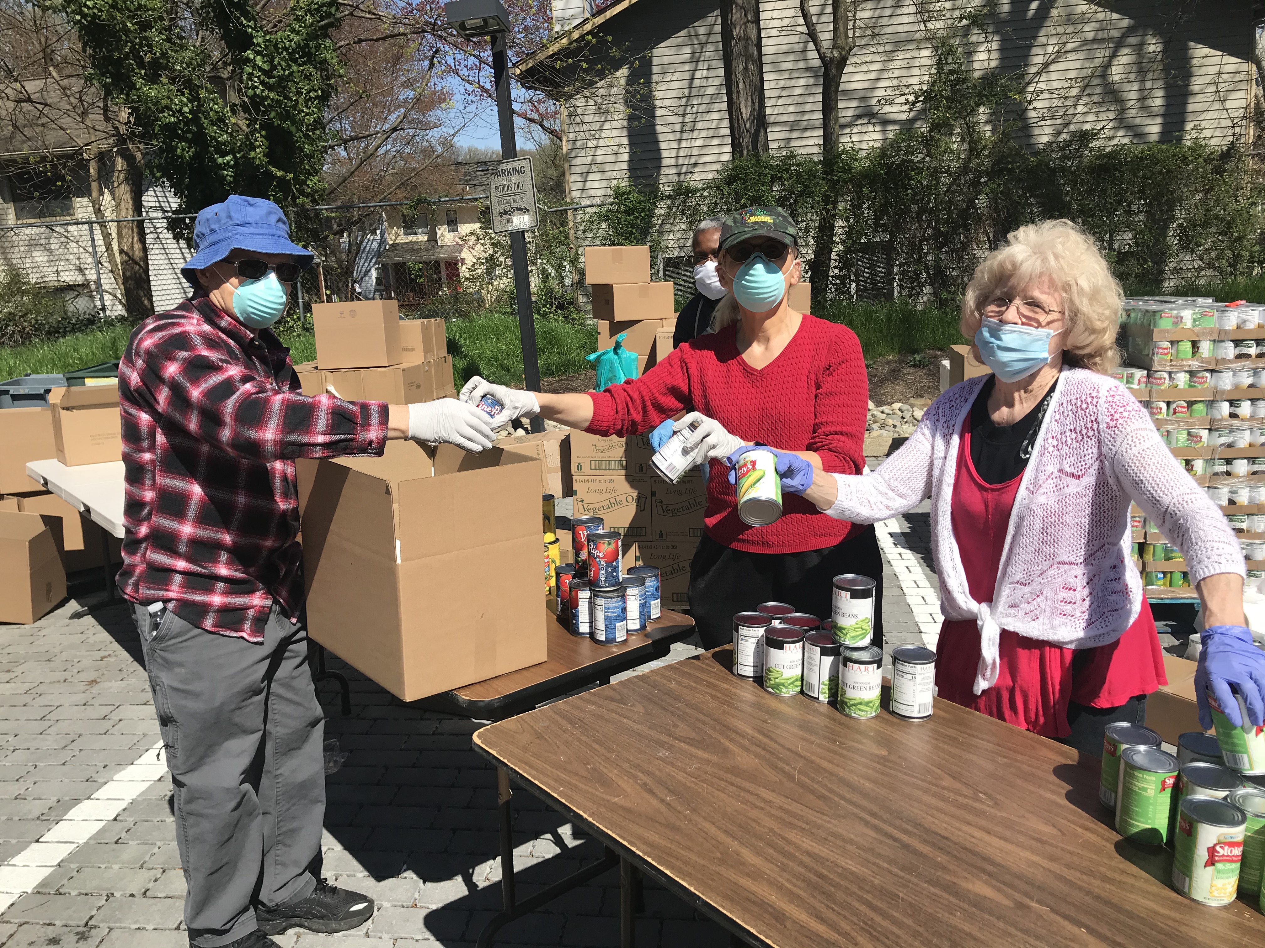 Volunteers of Adventist Community Services Greater Washington sort cans while wearing gloves and masks. 