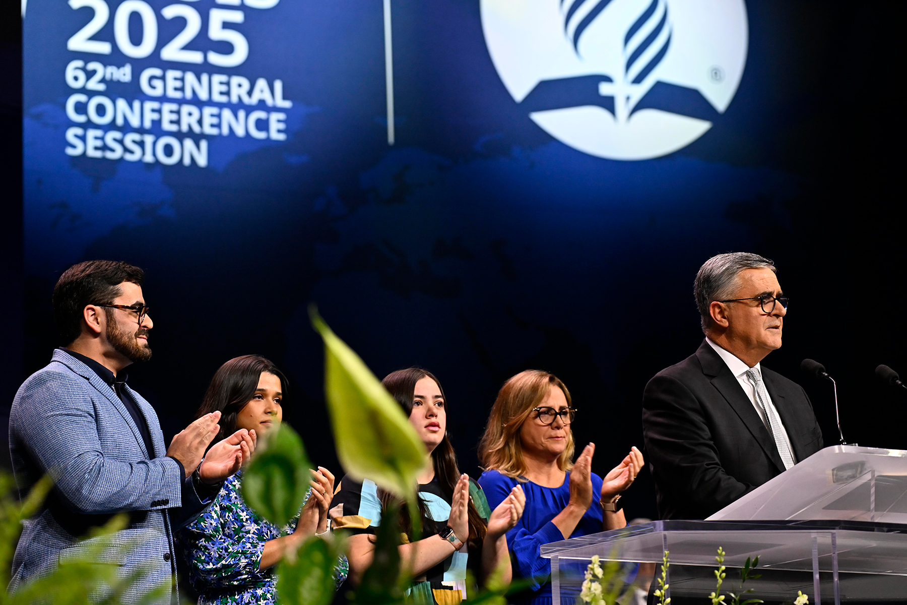 Picture of a man in the foreground with wife and three children in the background on a stage.
