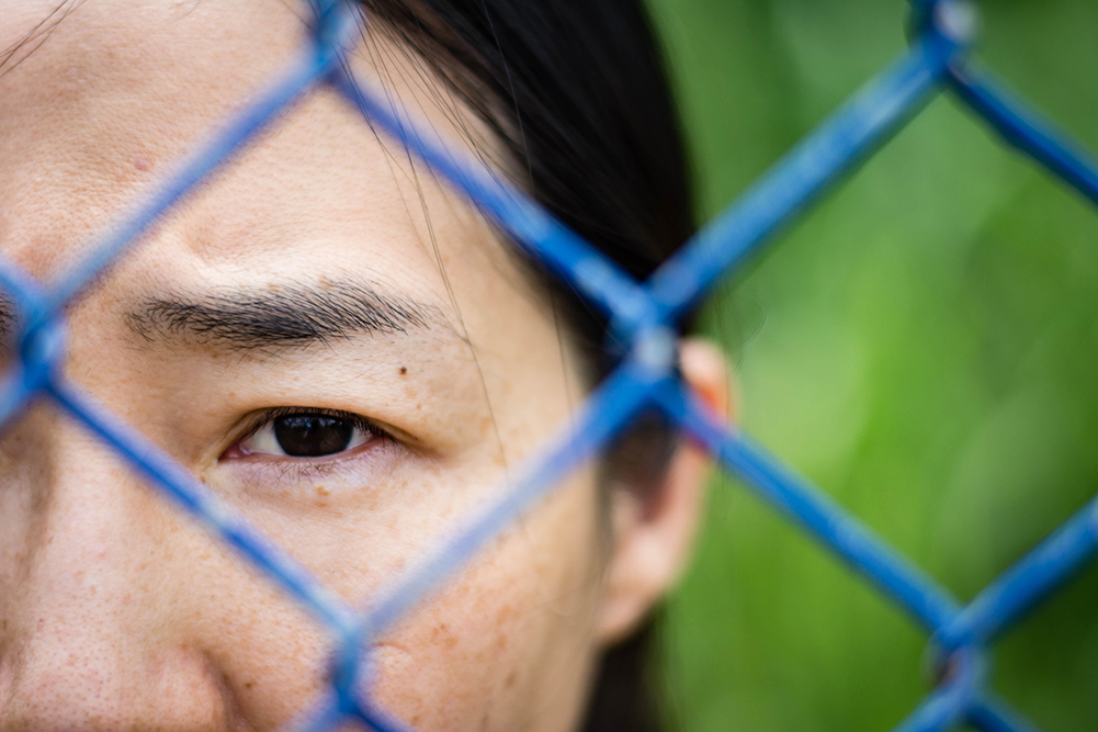 young woman looking through fence