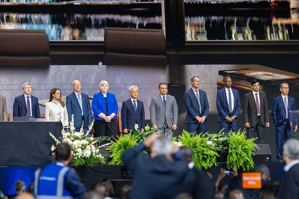 A diverse, formally dressed group of men and women stand on a stage.