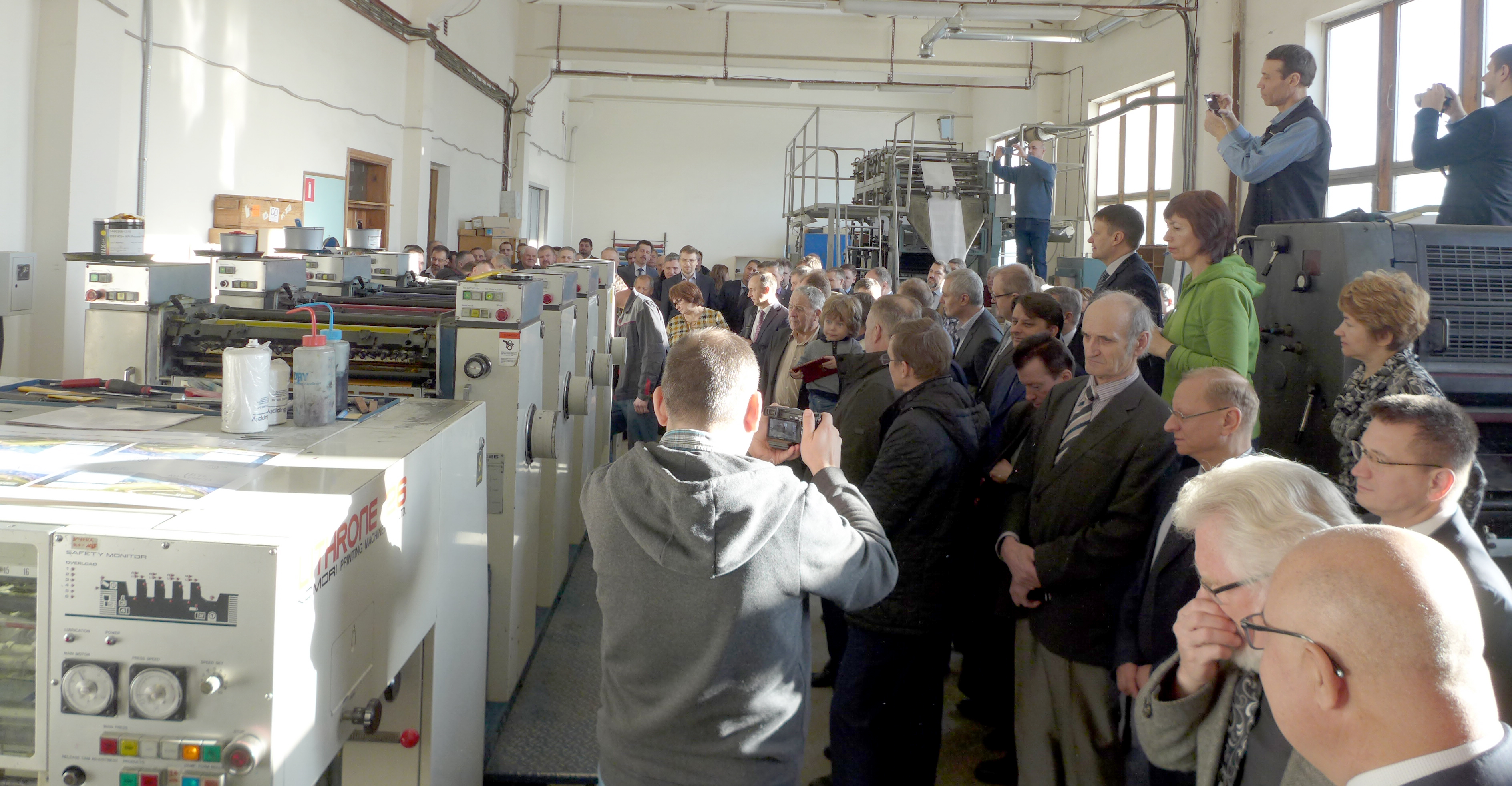 At the Source of Life Publishing House, a group of employees, officers, and College Press representatives watch as the press runs its first test.