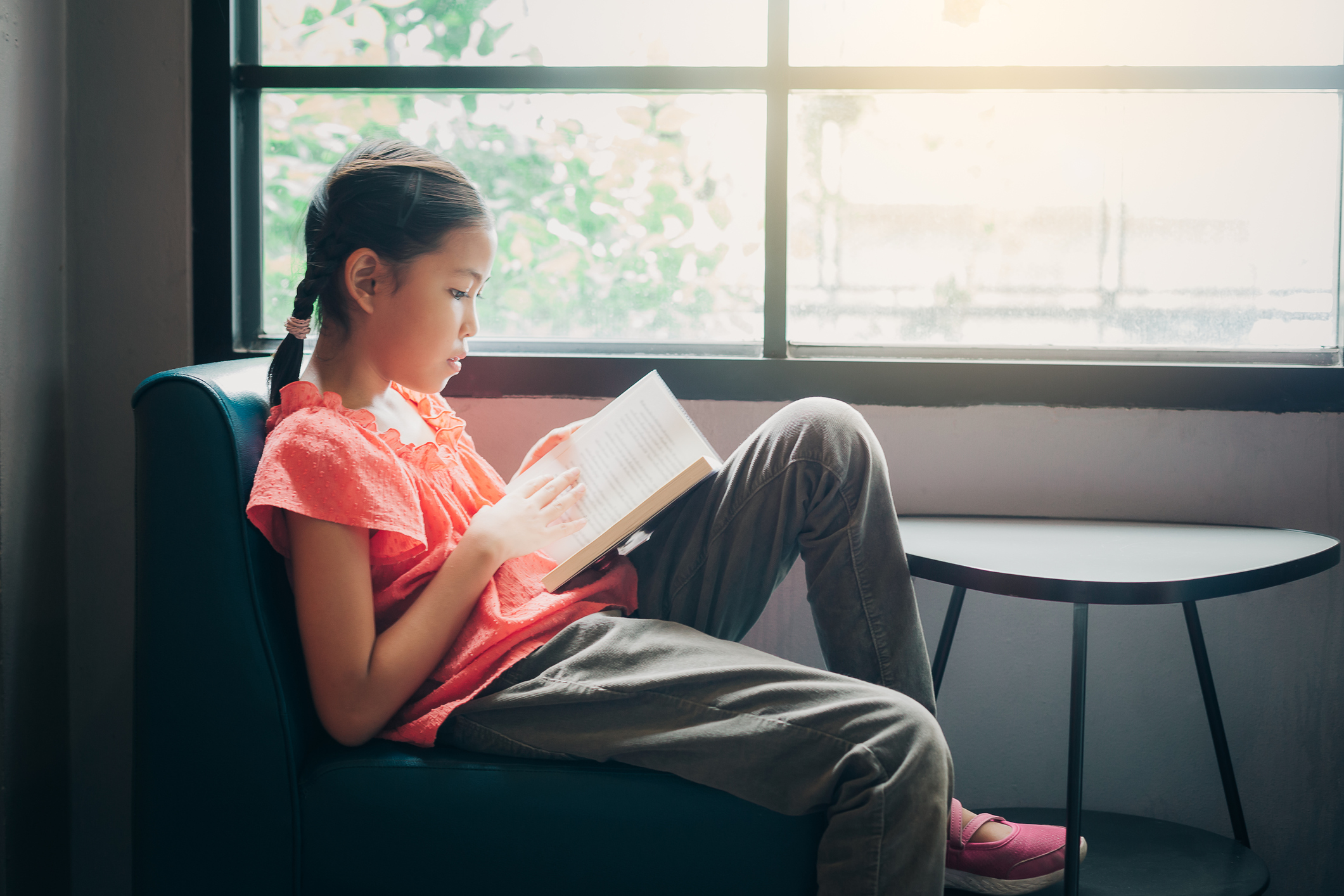 stock photo of Asian girl reading by window