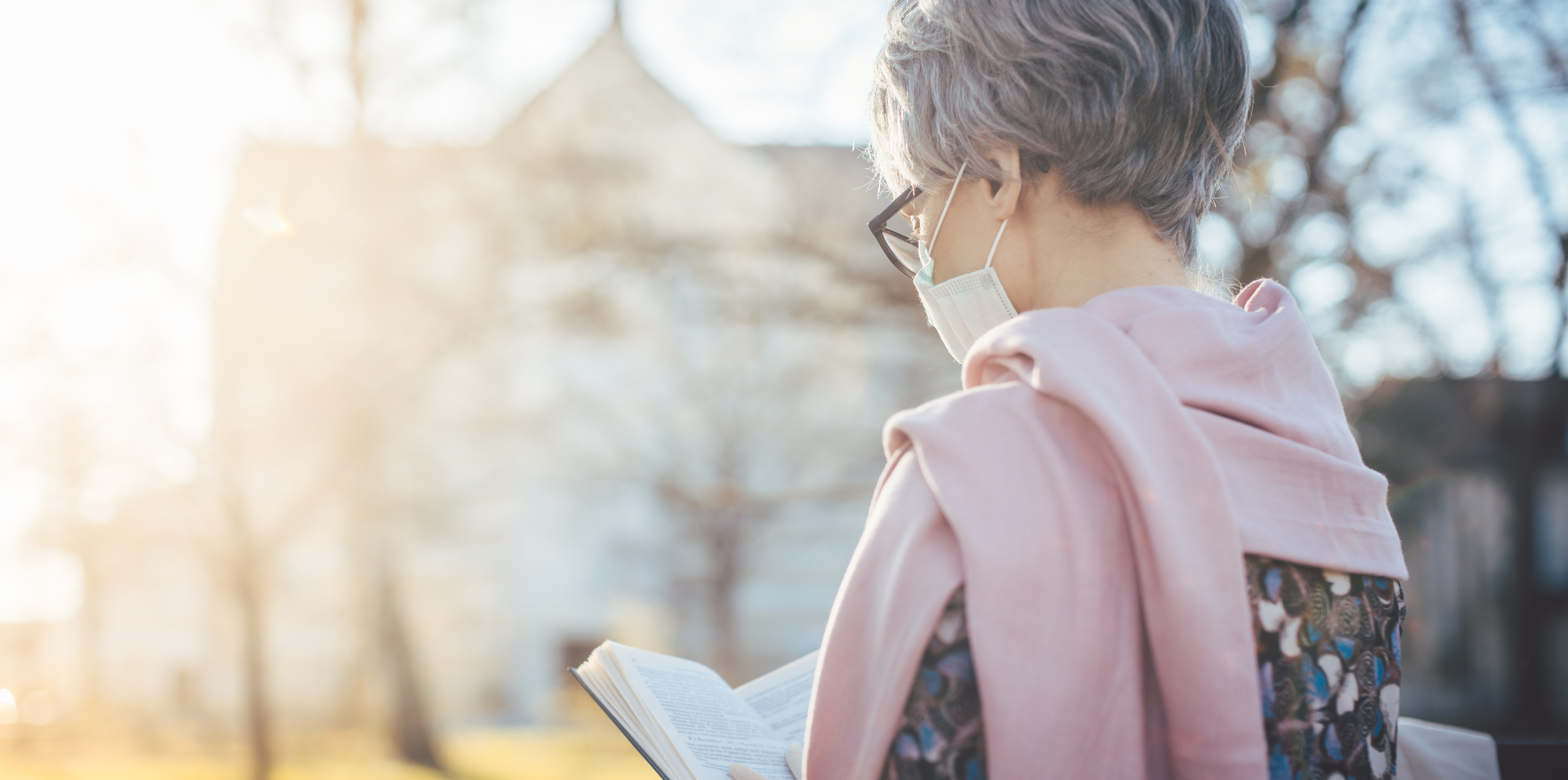 woman in mask reading Bible