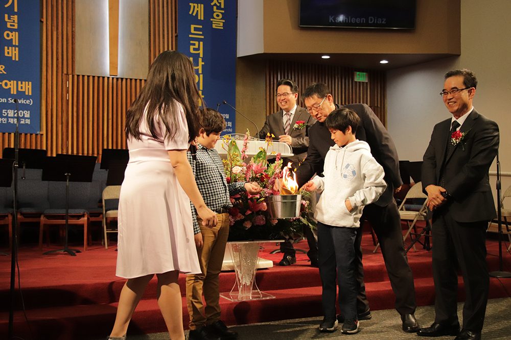 Diaz (left), with the help of two young volunteers, burns the mortgage papers.