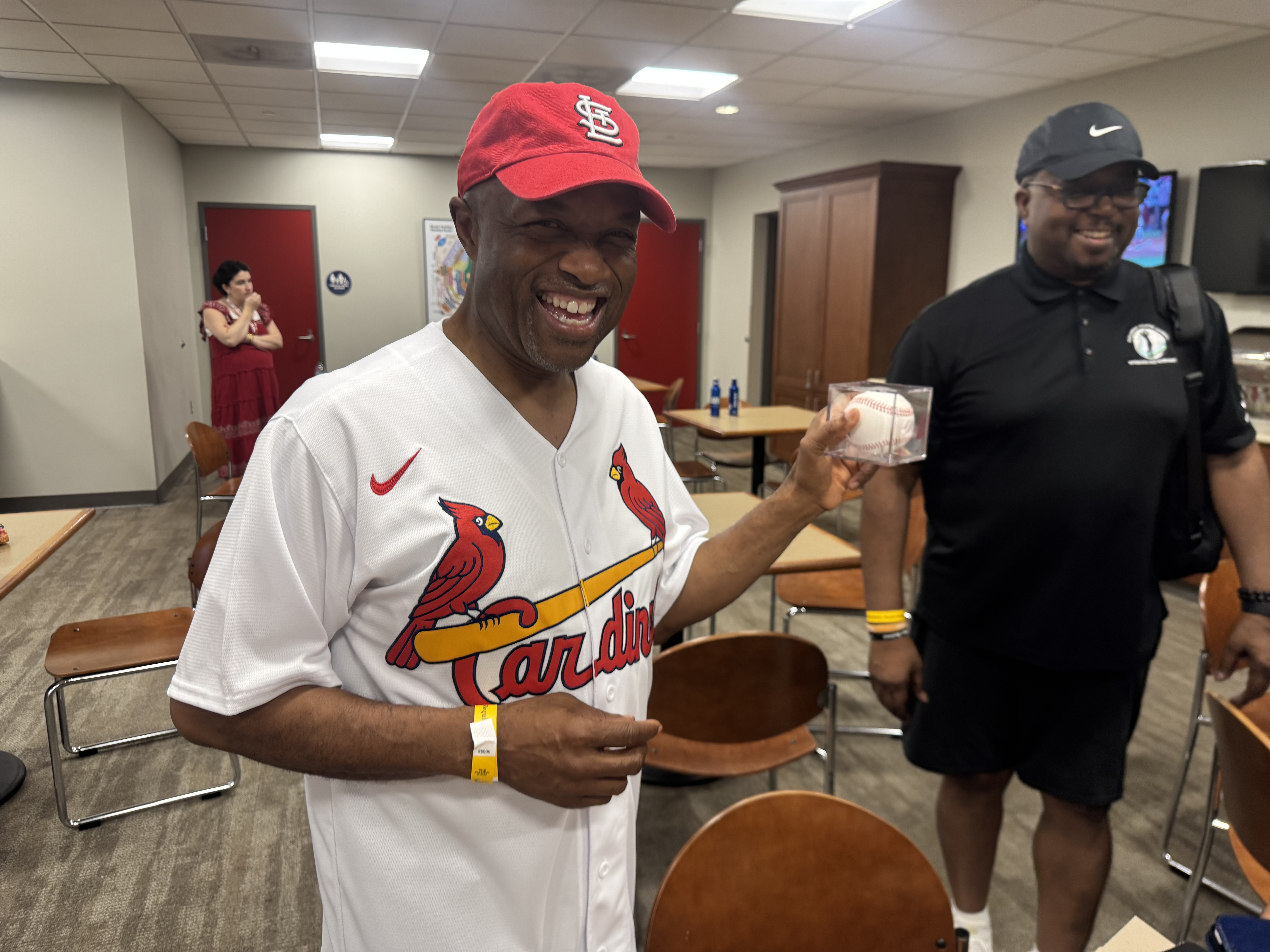 Middle age Black man in Cardinals shirt with baseball smiles