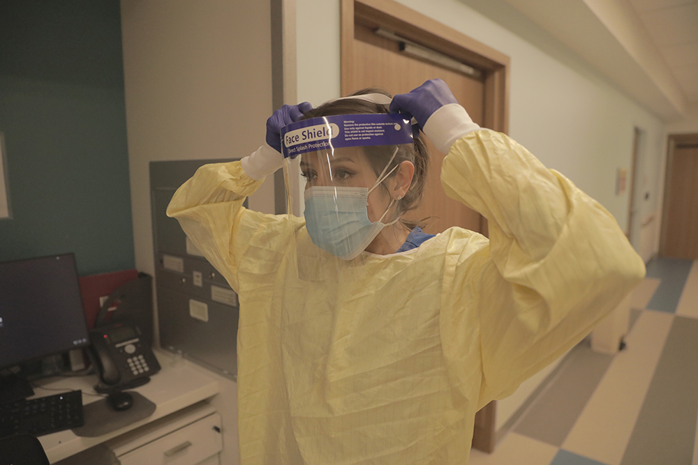 Tara Wamack, a registered nurse in the intensive care unit at White Oak Medical Center, suits up in new protective gear.
