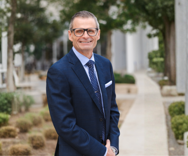 Middle aged caucasian man portrait outside on sidewalk with greenery around