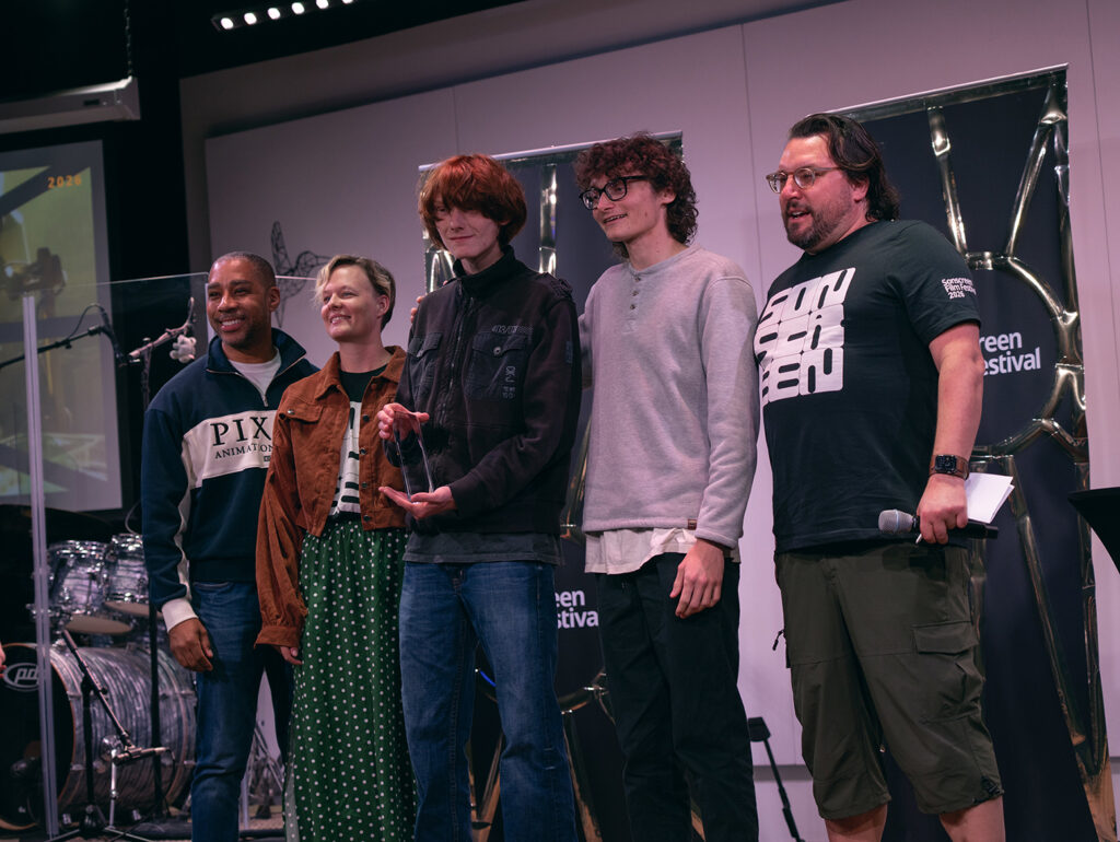 Five people pose for a photo during the Sonscreen awards ceremony. In the center is someone holding  an award. 