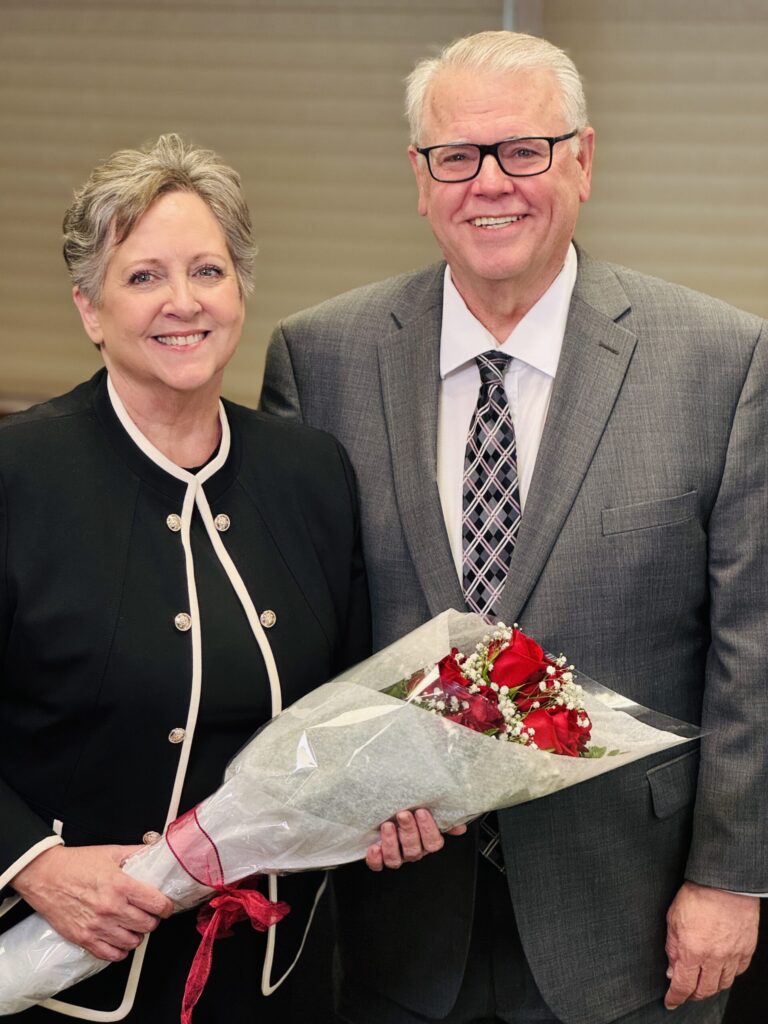Caucasian, middle/late age male and female posing with bouquet of flowers
