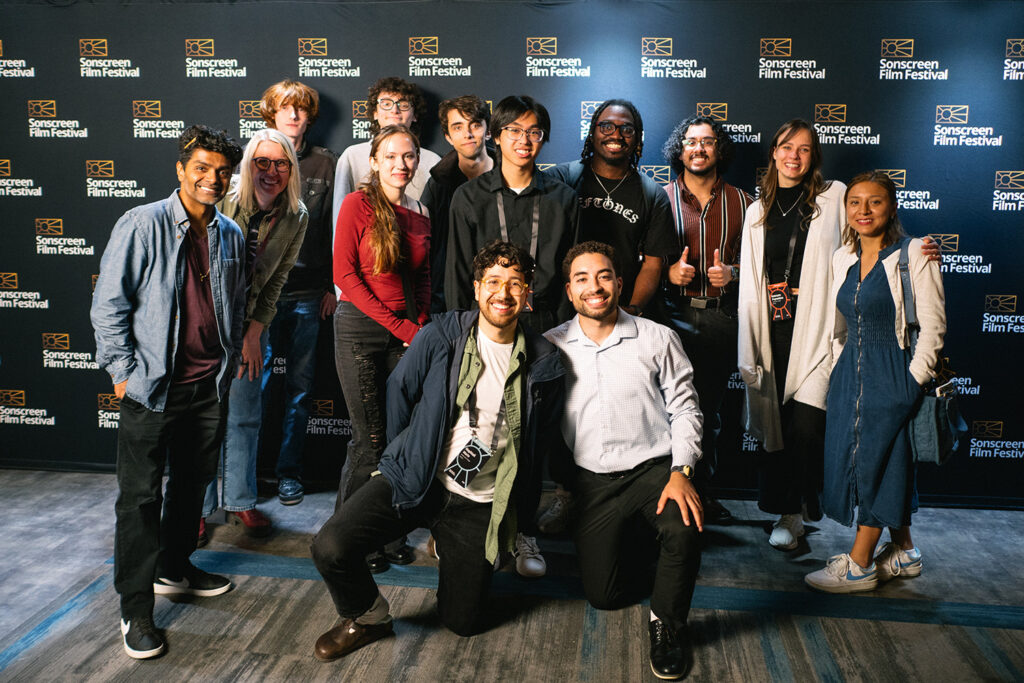 Group of college students posing in front of a film festival step-and-repeat backdrop